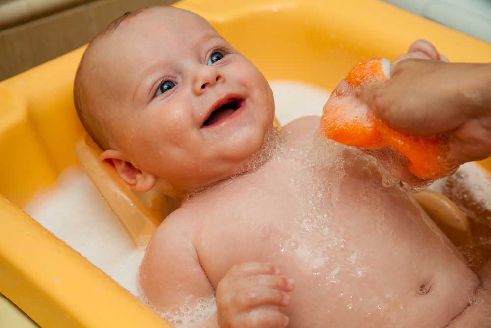 Малыша моют в ванночке