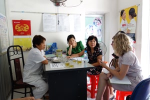 Group of lady health workers sitting around table in office.